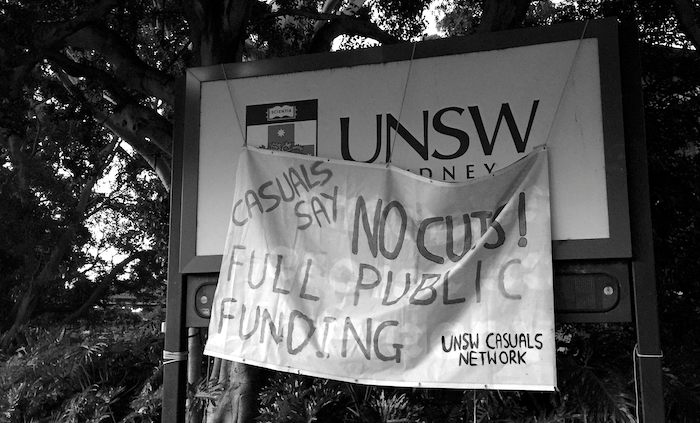 A protest sign with the words 'Casuals Say No Cuts, Full Public Funding' hanging from a UNSW campus billboard